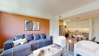 This contemporary 640 square foot apartment showcases a thoughtful layout that maximizes space and functionality. The open-concept design seamlessly integrates the living room, dining area, and kitchen, creating a spacious feel. The kitchen features stainless steel appliances, light wood cabinetry, and a compact dining set, perfect for intimate meals.

The living room is adorned with a plush blue sectional sofa, complemented by a vibrant orange accent wall and modern artwork. Large windows flood the space with natural light and offer picturesque views of the surrounding greenery. Hardwood floors run throughout, adding warmth and continuity to the space.

The bedroom, measuring 190 square feet, boasts a king-size bed with a navy upholstered headboard. It includes ample storage with a sleek black dresser and built-in closet. The bathroom features a modern design with a glass-enclosed shower, floating vanity, and crisp white tiles.

Thoughtful touches like track lighting, contemporary art pieces, and strategically placed plants enhance the overall aesthetic. The apartment's design strikes a balance between functionality and style, making efficient use of every square foot while maintaining a bright, airy, and inviting atmosphere.