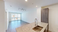 Located at 350 Village Dr in King of Prussia, PA, this well-appointed 1-bedroom, 2-bathroom residence offers a thoughtfully designed layout with modern finishes throughout. The open-concept kitchen and living area serves as the heart of the home, where the kitchen impresses with rich wood-tone cabinetry extending to the ceiling, stainless steel appliances including a refrigerator, range, and microwave, and a generous granite island with a deep double undermount sink and a pull-down faucet. Recessed lighting and light wood-style flooring add warmth and cohesion to the space. The living room benefits from large sliding glass doors that invite abundant natural light and offer views of the surrounding community. The bedroom is a comfortable retreat featuring a ceiling fan, a window with natural light, and direct access to a spacious walk-in closet outfitted with wire shelving for ample storage. Two well-appointed bathrooms include a full bath with a granite-topped vanity, wood-tone cabinetry, a tub-shower combo clad in large-format marble-look tile, and modern light fixtures. The second bath mirrors these upscale finishes, maintaining a clean and cohesive aesthetic throughout the residence.