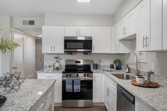 Cocina con encimeras de granito, electrodomésticos de acero inoxidable y gabinetes modernos. - Blakely