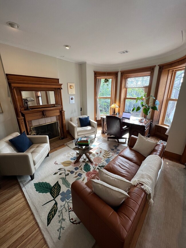 Hermosa sala de estar frontal con chimenea original, pisos de madera originales y ventanas curvas. - 938 W Newport Ave