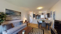 Located at 375 Marche Chase Dr in Eugene, Oregon, this single-floor unit offers a well-designed, open-concept layout that seamlessly connects the living, dining, and kitchen areas. The living room is a comfortable and inviting space, anchored by a tiled fireplace and large windows with vertical blinds that allow generous natural light. A sliding glass door provides direct access to the outdoors. The kitchen features dark espresso-toned cabinetry, light countertops, a stainless steel refrigerator, and a stainless electric range, complemented by a breakfast bar peninsula that opens to the dining area. The dining space accommodates a full-sized table and flows effortlessly into the living room, making the area ideal for both everyday living and entertaining. Two carpeted bedrooms offer quiet retreats, each with large windows and ample natural light. The unit includes two bathrooms: one with a shower/tub combination and a dark-cabinet vanity with hardwood-style flooring, and a second with an extended vanity, large mirror, and shower. The overall aesthetic is modern and neutral, with consistent dark cabinetry accents and light walls throughout, creating a clean and cohesive living environment.