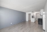 Located at 3505 W 139th St in Hawthorne, California, this efficient single-floor unit offers a well-organized layout comprising a living area, a kitchenette, and a full bathroom. The open living space is finished with light-toned laminate wood flooring and neutral gray walls, creating a clean, modern aesthetic. A textured popcorn ceiling runs throughout, and a large sliding window with vertical blinds allows natural light to fill the room, enhancing the sense of openness. The kitchen is thoughtfully appointed with white cabinetry, a mosaic tile backsplash, a stainless steel sink, a gas range with a built-in microwave above, and a wall-mounted heating unit nearby. The white cabinetry provides ample storage while maintaining a bright, tidy appearance. The bathroom features a full bathtub and shower combo with a handheld showerhead, clean white surround panels, and classic chrome fixtures. The overall design is practical and move-in ready, with consistent flooring and a cohesive neutral color palette throughout. The unit's efficient use of space makes it a functional option in the Hawthorne area of Los Angeles County, close to local amenities and major thoroughfares.