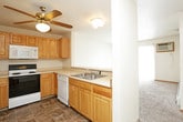 This single-floor residential unit offers a practical and functional layout designed for comfortable everyday living. The kitchen is well-equipped with warm honey-toned wood cabinetry providing ample storage, light-colored countertops, a full suite of white appliances including a refrigerator, electric range, built-in microwave, and dishwasher, all set atop durable tile flooring in an earthy, stone-like pattern. A pass-through opening connects the kitchen to the living area, enhancing the open feel between the two spaces.

The living area features neutral-toned carpet, a textured ceiling, a ceiling fan with light fixture, and a sliding glass door fitted with vertical blinds that invites natural light and provides outdoor access. A wall-mounted air conditioning unit and baseboard heating ensure year-round climate comfort.

The bedrooms continue the carpeted flooring and include ceiling fans, windows with blinds, baseboard heating, and individual wall-mounted AC units, creating well-ventilated and comfortable retreats.

The bathrooms are finished with the same tile flooring found in the kitchen, featuring light wood vanity cabinetry, solid-surface countertops, and clean white fixtures. One bathroom includes a full tub-shower combination, while another functions as a half bath with a toilet and vanity. The overall ambiance is clean, neutral, and move-in ready.