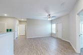 Located at 3151 Boulevard de Sevilla in Foley, Alabama, this single-floor residence offers a clean, modern design throughout. The open living area is finished with light wood-style flooring and neutral-toned walls, creating a bright and welcoming atmosphere. Ceiling fans with integrated lighting are present in the main living spaces, complementing the recessed lighting overhead. Natural light filters in through windows, and a private exterior door provides convenient access.

The kitchen is well-equipped with granite countertops, gray shaker-style cabinetry, a stainless steel undermount sink, and a full suite of stainless steel appliances including a range, microwave, and refrigerator. The layout offers ample counter and storage space, connecting seamlessly to the living and dining areas.

Bedrooms are carpeted for comfort, each featuring ceiling fans and generous closet access. The bathrooms maintain a consistent design language, with granite-topped vanities set in gray cabinetry, undermount sinks with brushed nickel fixtures, and tub-shower combinations. Clean white finishes and neutral wall tones keep the bathrooms feeling bright and functional. Overall, the unit presents a cohesive, contemporary aesthetic suited to comfortable everyday living.