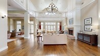 This expansive 4,130 square foot property in Charleston, SC offers a harmonious blend of modern amenities and classic charm. The single-story layout encompasses three distinct living rooms, providing ample space for relaxation and entertainment. The heart of the home features an open-concept design, seamlessly integrating the kitchen, dining, and living areas.

The kitchen is a standout, with sage green cabinetry contrasting beautifully against exposed brick walls. Stainless steel appliances and a large island with a marble countertop complete this gourmet space. Hardwood floors flow throughout, adding warmth and continuity to the interior.

Large windows and French doors flood the rooms with natural light, while high ceilings create an airy ambiance. The property boasts an inviting entrance and a stunning hallway with brick flooring and built-in mailboxes, suggesting a multi-unit or community setting.

Outdoor spaces are equally impressive, with a covered porch overlooking lush greenery and a tree-lined sidewalk. The exterior features classic Southern architecture with white columns and brick accents. Inside, a fireplace in one of the living areas adds a cozy touch to the otherwise spacious and bright interior.

The property's attention to detail is evident in its carefully chosen light fixtures, elegant window treatments, and thoughtful architectural elements, making it a truly remarkable space that balances comfort with sophistication.