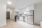 Located at 2701 Eglinton Ave W in Toronto's Mount Dennis neighbourhood, this efficiently designed single-floor studio unit offers a clean, modern aesthetic throughout. The interior is finished in a bright, all-white palette that maximizes the sense of space and light.

The kitchen is a standout feature, outfitted with crisp white cabinetry, a herringbone-patterned tile backsplash, stainless steel appliances including a freestanding range, refrigerator, and dishwasher, as well as a stainless steel sink. Track and recessed lighting illuminate the workspace effectively. In-unit laundry is also conveniently tucked within the unit.

The open living area flows seamlessly from the kitchen, featuring light wood-tone laminate flooring and a large window that invites natural light and offers a view of the surrounding greenery. A baseboard heating unit runs beneath the window, ensuring year-round comfort.

The bathroom is finished with classic white subway tile surrounding a full soaking tub and shower combination, with chrome fixtures adding a polished touch. White tile flooring completes the clean, cohesive look.

Throughout the unit, recessed and flush-mount ceiling lighting provides consistent illumination, while the consistent white walls and light flooring create a bright, airy atmosphere well-suited to comfortable urban living.