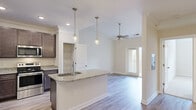 Located at 20 Pine Glen Dr in Clayton, NC, this single-story residence offers a thoughtfully designed layout across a comfortable footprint. The open-concept kitchen and dining area serves as the heart of the home, showcasing rich dark-espresso cabinetry, granite countertops, and a full suite of stainless steel appliances including a French door refrigerator, electric range, and built-in microwave. A peninsula island with an undermount sink and pendant lighting above creates a natural gathering point and additional prep space. A dedicated pantry closet provides ample storage. The living area extends naturally from the kitchen, featuring light hardwood-style flooring, crown molding, a ceiling fan, and a glass-panel door that introduces natural light. The dining area is defined by elegant crown molding and a multi-light chandelier. The generously sized primary bedroom features plush carpeting and a tray ceiling with crown molding detail. Its walk-in closet is outfitted with wire shelving and hanging systems on multiple walls. The full bathroom includes a dual-sink granite vanity with dark cabinetry, a large mirror, and light tile flooring, completing this well-finished residence.