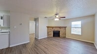 This single-floor, 2-bedroom, 2-bathroom home offers a practical and inviting layout with consistent wood-look flooring throughout. The open living room serves as the heart of the home, anchored by a classic brick fireplace with a wood mantel and complemented by a ceiling fan with light fixture. Natural light filters in through a window, and a textured ceiling adds a traditional touch to the space.

The kitchen features white cabinetry with ample upper and lower storage, a white electric range, a built-in dishwasher, and a single-basin sink set into a light-toned countertop — all arranged in an efficient U-shaped layout.

The primary bedroom offers a generous footprint, a ceiling fan, a window for natural light, and includes a dedicated closet. The second bedroom provides a comfortable, well-proportioned space with easy access to the hallway. Both bathrooms are equipped with tub-shower combos; one bathroom features a vanity with a stone-patterned countertop and white cabinetry, while the other is finished with clean, minimal fixtures. Wood-look flooring carries into the bathrooms, maintaining a cohesive aesthetic. A closet provides additional storage. The overall ambiance is clean, neutral, and move-in ready.