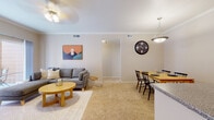 This single-floor residence offers a thoughtfully designed open-concept layout that seamlessly connects the living, dining, and kitchen areas. The living room is carpeted and bathed in natural light, featuring crown molding, a ceiling fan, and sliding glass doors that open onto a private balcony overlooking lush greenery — an inviting spot for outdoor relaxation. The adjacent dining area flows naturally from the living space, making it well-suited for both everyday meals and entertaining.

The kitchen is equipped with light wood cabinetry, granite-style countertops, a full suite of white appliances, and a peninsula that doubles as a breakfast bar. Tile flooring grounds the kitchen and entry area, providing a practical contrast to the plush carpet found throughout the rest of the home.

The residence includes two bedrooms, each carpeted and filled with natural light from well-positioned windows. One bedroom benefits from a spacious walk-in closet with built-in shelving, offering generous storage. The full bathroom features tile flooring, a single-sink vanity with white cabinetry, and a tub-shower combination. Crown molding and consistent neutral tones throughout lend the space a cohesive, comfortable character.
