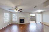 Located at 101 S Twin Creek Dr in Killeen, TX, this single-floor, 2-bedroom, 1-bathroom residence offers a well-organized layout with a comfortable mix of living spaces. The open living room serves as the heart of the home, showcasing rich hardwood-style flooring, a ceiling fan with light fixture, and a tile-surround fireplace that anchors the room. Natural light streams in through multiple windows with blinds, and a sliding glass door opens to a private patio, extending the living space outdoors. The kitchen runs in a galley configuration, featuring warm wood cabinetry, light countertops, black appliances including a range, microwave, refrigerator, and dishwasher, as well as a double sink. Light plank flooring ties the kitchen together efficiently. Both bedrooms are carpeted and equipped with ceiling fans, offering a quiet, comfortable retreat. The primary bedroom includes a walk-in closet with built-in shelving. The full bathroom features a tiled tub-shower combination. Additional conveniences include a dedicated laundry area, hallway, and closet. Textured ceilings are present throughout the home, adding a classic residential feel to the overall design.