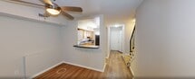 This 920-square-foot, two-story residence at 5130 Goldsboro Dr, Unit 6, Hampton, VA offers a functional and well-organized layout across two floors. The ground floor (470 sq ft) features a bright living room with light wood-style laminate flooring and a private entry door with a window that allows natural light to fill the space. Adjacent to the living room is the kitchen, equipped with warm oak cabinetry, dark granite-style countertops, a stainless steel sink, and a window overlooking the exterior. A full bathroom with a clean white tub/shower combo is also located on this level. A staircase with a metal railing connects to the upper floor (450 sq ft), which houses both bedrooms and a second full bathroom. The primary bedroom measures 210 sq ft and includes a ceiling fan, wood-style flooring, and a closet. The second bedroom features neutral carpet, a built-in closet with bifold doors, and a window with natural views. Both bedrooms are finished with neutral tones throughout. The second bathroom mirrors the first with a tub/shower unit and warm wood-toned vanity cabinetry. The unit offers a straightforward, comfortable layout well-suited for everyday living.
