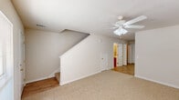 This two-story townhouse in Hammond, Louisiana, presents a straightforward and functional layout across two levels. The main floor features a carpeted living area brightened by a window overlooking the outdoors, with a ceiling fan overhead and a staircase leading to the upper level. The kitchen is outfitted with warm oak cabinetry, light countertops, a black refrigerator, and a double sink, all set on light wood-look flooring. A half bath is conveniently located on this level, featuring a wood-vanity and a tub-shower combination.

Upstairs, the primary bedroom is a standout, offering carpet flooring, a ceiling fan, a walk-in closet, and French doors that open to an outdoor view. A second carpeted bedroom includes its own walk-in closet and a window for natural light, with a ceiling fan adding comfort. The upper level also features a full bathroom with a vanity, toilet, and tub-shower, as well as a laundry closet with hookups. The angled roofline is visible in the upper hallway, adding architectural character. Neutral beige tones and white trim carry throughout, creating a clean, cohesive aesthetic across the entire home.