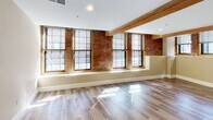 This 960 square foot loft apartment, located in Unit LL20 of Lofts 34, seamlessly blends industrial charm with modern comfort. The space boasts two bedrooms, including a primary bedroom of 150 square feet, and one bathroom. The open-concept layout features a combined kitchen and living room, creating a spacious feel.

The loft's character shines through with exposed brick walls and wooden beams, adding warmth and texture to the space. Large windows allow ample natural light to flood the rooms, enhancing the airy atmosphere. The flooring throughout is a stylish wood-look material, unifying the entire apartment.

The kitchen is equipped with contemporary stainless steel appliances, granite countertops, and ample wooden cabinetry. A convenient in-unit laundry area with stacked washer and dryer adds practicality to the living space.

The bedrooms offer a tranquil retreat, with neutral tones and carpeted floors in some areas. The bathroom, while not pictured, likely continues the modern aesthetic found throughout the apartment.

This loft apartment successfully marries industrial elements with contemporary design, creating a unique and inviting living space that maximizes its 960 square feet.