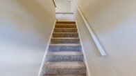 Located at 4441 E Honeygrove Ct in Virginia Beach, Virginia, this two-story home offers a practical and comfortable layout across two levels. The main living level is the heart of the home, featuring a combined dining and living area with plush carpeting, warm neutral tones, and a decorative white iron staircase railing that adds a touch of character. The kitchen is equipped with white cabinetry, a stainless steel range, and hardwood-style flooring that extends through the dining area and into a dedicated laundry space, which also includes a walk-in closet for added utility.

Upstairs, two carpeted bedrooms provide comfortable retreats, each benefiting from natural light through windows with blinds. The spacious primary bedroom features dual closets with louvered bi-fold doors, offering abundant storage. The second bedroom also includes a closet and serene outdoor views. Both rooms share neutral walls and textured ceilings. The home's single full bathroom is well-appointed with white cabinetry, a tiled tub-and-shower combination, hardwood-style flooring, and brushed nickel grab bars. With six closets total spread throughout, storage is a standout feature of this well-organized Virginia Beach home.