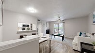 This efficiently designed one-bedroom, one-bathroom unit is laid out across a single floor, making thoughtful use of its compact footprint. The open-concept main area seamlessly connects the living room, dining area, and kitchen, creating a cohesive and functional living space. The living room features wood-look flooring, a ceiling fan, a fireplace, and a sliding glass door that floods the space with natural light and provides direct access to an outdoor patio area.

The kitchen is configured in a galley style, outfitted with white cabinetry, subway tile backsplash, white countertops, and black appliances including a refrigerator, electric range, microwave, and dishwasher. A pass-through window connects the kitchen to the dining area, where a breakfast bar with stools offers additional seating alongside the dedicated dining space.

The bedroom is a comfortable size, featuring a ceiling fan, wood-look flooring, and a window that allows natural light. The bathroom includes a full shower-tub combination with white tile surround. Additional features include a hallway, a closet for storage, and textured ceilings throughout.