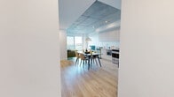 Located at 7001 Rue Prudent-Beaudry in Mascouche, Quebec, this well-appointed 2-bedroom, 1-bathroom unit offers a contemporary design with a clean, minimalist aesthetic throughout. The space is unified by light hardwood flooring and striking exposed concrete ceilings, giving it an urban, industrial character balanced by bright white walls.

The living room is a standout space, featuring large sliding glass doors that open to a balcony and frame sweeping views of the surrounding landscape. Natural light flows generously through floor-to-ceiling windows, creating an airy and open atmosphere.

The kitchen is efficiently designed with a galley layout, featuring light wood cabinetry paired with upper matte white cabinets, white quartz countertops, a subway tile backsplash, and stainless steel appliances including a range, refrigerator, and dishwasher.

The primary bedroom benefits from large windows with the same panoramic outdoor views, exposed concrete ceiling, and warm hardwood floors, providing a calm and comfortable retreat. The second bedroom is equally bright and versatile.

The bathroom is finished in a clean, modern style with large-format floor tiles and a frameless sliding glass shower enclosure with white tile surround. Throughout the unit, the design prioritizes natural light, clean lines, and functional living.