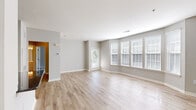 Located at 100 Cornerstone Drive in Glen Mills, PA, this well-appointed one-bedroom, one-bathroom residence offers a thoughtfully designed single-floor layout. The spacious living room is a standout feature, highlighted by a curved bay window arrangement that floods the room with natural light. Light-toned hardwood-style flooring runs throughout the main living areas, complementing the soft neutral gray walls and clean white trim for a modern, airy aesthetic. A glass-paneled door provides direct outdoor access from the living area. The kitchen is outfitted with crisp white shaker-style cabinetry, dark granite countertops, and a full suite of stainless steel appliances including a range, dishwasher, and microwave, all set atop matching light-wood flooring. The generously sized primary bedroom features plush carpeting, a walk-in closet, and a window with outdoor views. The full bathroom includes a white vanity with ample drawer storage, a large mirror with overhead lighting, and hardwood-style flooring. A dedicated laundry room with a full-size side-by-side washer and dryer adds everyday convenience. The overall design is clean, modern, and move-in ready.