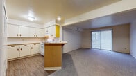 This single-floor residence at 2652 Clydesdale Dr in South Bend, Indiana, offers a straightforward, functional layout with a cohesive open design connecting the kitchen and living areas. The kitchen is well-equipped with ample white cabinetry featuring warm wood-toned hardware, generous countertop space with a wood-edged finish, a white gas range, a refrigerator, and an under-cabinet range hood. A peninsula with a wood-paneled base extends into the living space, providing additional prep area and casual seating. Wood-look plank flooring runs throughout the kitchen, offering durability and easy maintenance.

The living area is carpeted and opens directly from the kitchen peninsula, creating a seamless, spacious feel. A full-width sliding glass door fitted with vertical blinds allows natural light to fill the room and provides access to the outdoors. Additional closet storage is accessible from the living space, as seen through the louvered bi-fold doors. A separate carpeted bedroom features a large window with outdoor views and ample wall space. The bathroom includes wood-look flooring, a vanity with under-sink storage, towel bars, and a separate shower area. Overall, the space presents a clean, neutral palette throughout.