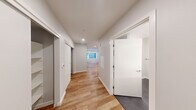 Located in Seattle's Capitol Hill neighborhood, this thoughtfully designed one-bedroom, one-bathroom unit offers a clean, modern aesthetic throughout its efficiently laid-out single floor. Light wood-style flooring runs continuously through the main living areas and hallway, creating a cohesive and warm feel.

The kitchen is a standout feature, outfitted with full stainless steel appliances including a French door refrigerator with ice maker, electric range, over-the-range microwave, and dishwasher. White upper cabinetry is paired with slate-gray lower cabinets, accented by white quartz countertops and a classic subway tile backsplash. Recessed lighting illuminates the space, and a window allows natural light to filter in.

A wide hallway connects the main living area to the private spaces, with a sliding closet door offering convenient storage access. The bedroom features plush carpeting, soft neutral walls, and a window that brings in natural light. The bathroom is finished with a modern wood-toned vanity, white countertop, backlit mirror, and matte black hardware accents set against neutral gray tile flooring. A wall-mounted mini-split unit provides efficient climate control throughout the unit.