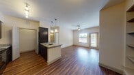 This single-story residence is designed with a practical and modern layout that balances open communal spaces with private retreats. The kitchen serves as a central highlight, featuring dark espresso cabinetry, granite countertops, and black appliances including a refrigerator, range, and built-in microwave. A peninsula island with an undermount sink and pendant lighting above extends the workspace while connecting seamlessly to the living area. Track lighting and hardwood-style flooring run throughout the kitchen and main living space, enhancing the cohesive, contemporary aesthetic. The living area is generously proportioned, with a ceiling fan overhead and a glass door leading to an outdoor balcony, allowing natural light to flow freely.

The bedrooms are carpeted for comfort and include ceiling fans and windows with horizontal blinds, offering outdoor views and natural light. Both bathrooms are finished with granite-topped dark vanities and hardwood-style flooring. One bathroom features a tub-shower combination with full tile surround, while the other offers a similar layout with a double-sink vanity. A dedicated laundry closet is accessible directly from the kitchen corridor, adding functional convenience to the overall floor plan.