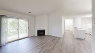 Located at 2450 Masons Ferry Dr in Herndon, VA, this two-bedroom, two-bathroom residence offers a well-organized single-floor layout with a clean, neutral aesthetic throughout. Wood-style plank flooring runs continuously across the living areas, hallway, and bedrooms, lending warmth and visual cohesion to the space.

The living area serves as the heart of the home, featuring a classic fireplace as a focal point and a sliding glass door that opens to a private balcony with tree-lined views. A pendant light fixture highlights the adjacent dining area, which benefits from an open feel enhanced by vaulted-style wall height.

The hallway connects all rooms efficiently, with a built-in shelf providing added convenience. The primary bedroom is generously proportioned, offering a dedicated closet and direct access to its own full bathroom. The second bedroom receives abundant natural light through a pair of windows overlooking greenery, creating a bright and comfortable retreat. Each bathroom includes a tub-shower combination and a large mirror.

A dedicated laundry room houses a stacked washer and dryer unit, offering full in-unit laundry convenience. Two closets provide ample storage throughout the home. The overall design is understated and functional, making this Herndon residence a practical and inviting space.