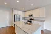 This well-appointed single-story residence at 7105 Hall Rd in Union City, GA offers a thoughtfully designed open-concept layout across a comfortable footprint. The modern kitchen serves as a central highlight, featuring crisp white shaker cabinetry extending to the ceiling, granite countertops, a large center island with an undermount sink, and a full suite of stainless steel appliances including a refrigerator, electric range, and built-in microwave. Rich hardwood-style flooring flows throughout, tying the spaces together cohesively. The open living and dining areas are bright and airy, benefiting from natural light streaming through a set of French doors that create a seamless connection to the outdoors. The spacious primary bedroom offers a clean, neutral palette with ample room for furnishings and includes dedicated closet space. An additional den provides flexible space for a home office or secondary living area. The full bathroom is well-appointed with a granite-topped vanity with white cabinetry, a tub/shower combination, and recessed lighting. A utility room and multiple closets add practical storage throughout. The overall ambiance is clean, modern, and move-in ready.
