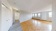 Located on the fourth floor at 1920 Weston Rd in Toronto's Weston neighbourhood, this one-bedroom, one-bathroom unit offers a practical and well-organized layout across a single floor. The living room is bright and welcoming, featuring classic parquet wood flooring and multiple windows that invite natural light while offering views of the surrounding Weston streetscape and skyline. Baseboard heating runs along the walls throughout, ensuring consistent warmth. The kitchen is outfitted with white cabinetry, a marble-style countertop, subway tile backsplash, and a stainless electric range, with light wood-tone vinyl flooring that distinguishes it from the rest of the unit. A doorway connects the kitchen directly to the living area, maintaining an open and accessible flow. The bedroom is a comfortable size, continuing the parquet flooring, and includes a built-in double closet for storage. A drop ceiling adds a distinct character to the bedroom. The bathroom features a full soaking tub with a tiled surround, chrome fixtures, and a safety grab bar. From the building's common areas, expansive views of the Weston commercial strip and the broader Toronto skyline are visible, reflecting the unit's convenient urban location.