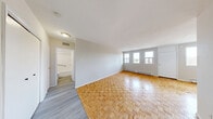 Located on the fourth floor at 1920 Weston Rd in Toronto's Weston neighbourhood, this one-bedroom, one-bathroom unit offers a practical and well-organized layout across a single floor. The living room is bright and welcoming, featuring classic parquet wood flooring and multiple windows that invite natural light while offering views of the surrounding Weston streetscape and skyline. Baseboard heating runs along the walls throughout, ensuring consistent warmth. The kitchen is outfitted with white cabinetry, a marble-style countertop, subway tile backsplash, and a stainless electric range, with light wood-tone vinyl flooring that distinguishes it from the rest of the unit. A doorway connects the kitchen directly to the living area, maintaining an open and accessible flow. The bedroom is a comfortable size, continuing the parquet flooring, and includes a built-in double closet for storage. A drop ceiling adds a distinct character to the bedroom. The bathroom features a full soaking tub with a tiled surround, chrome fixtures, and a safety grab bar. From the building's common areas, expansive views of the Weston commercial strip and the broader Toronto skyline are visible, reflecting the unit's convenient urban location.