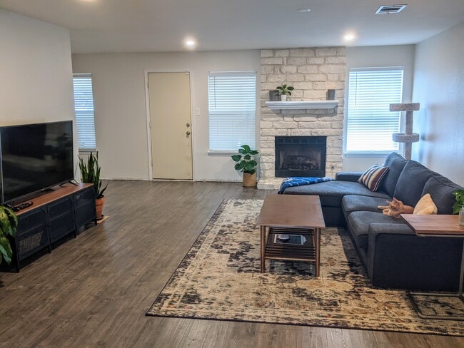 Living room with fireplace, back door access, and dining room to the left - 8645 Piney Creek Bend