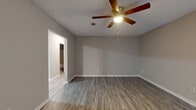 Located at 6900 Cantrell Rd in Little Rock, Arkansas, this single-floor residence offers a well-organized layout with consistent finishes throughout. The living areas feature wood-look luxury vinyl plank flooring and neutral gray walls, creating a clean and cohesive aesthetic. Ceiling fans with integrated light fixtures are present throughout the main living spaces, ensuring comfort and adequate lighting.

The galley-style kitchen is efficiently designed with warm honey-toned wood cabinetry, a marble-look countertop and backsplash, a stainless steel double-basin sink, and full appliances including a stainless steel refrigerator and electric range. Light-toned vinyl plank flooring runs throughout the kitchen, complementing the overall palette.

The living and dining areas are open and well-proportioned, with smooth transitions between rooms. One room features vertical blinds over a sliding glass door, allowing for natural light and outdoor access. A carpeted bedroom provides a softer underfoot experience, with a window offering natural light. Additional rooms with vinyl plank flooring offer flexible use as bedrooms or living spaces.

The bathroom is finished with light vinyl plank flooring, a marble-look vanity countertop, a white tiled tub-shower surround, and a grab bar for added accessibility. The textured ceilings are consistent throughout, adding a traditional residential character to the overall space.