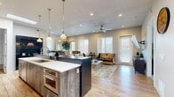 Located at 255 N 400 W in Salt Lake City, Utah, this thoughtfully designed 2-bedroom, 2-bathroom residence offers a modern, open-concept layout that seamlessly connects the kitchen, dining, and living areas. The chef's kitchen is a standout feature, showcasing weathered wood-tone cabinetry, a mosaic tile backsplash, stainless steel appliances including a professional-grade range and French door refrigerator, white quartz countertops, and a large island with bar seating and pendant lighting overhead. Light wood-style flooring flows throughout the main living areas, enhancing the bright and airy feel created by multiple windows and recessed lighting. The living room offers direct exterior access and is anchored by a ceiling fan, while the adjacent dining area comfortably accommodates a full dining set. The primary bedroom features plush carpet, a ceiling fan, and a natural light-filled window. The bathrooms are elegantly appointed, with the full bath displaying floor-to-ceiling stone-look tile, a walk-in glass shower, a soaking tub, and a wood-toned vanity with a vessel sink. A hallway connects the private bedroom quarters, completing this well-appointed and cohesive living space.