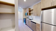 Located at 1030–1032 Union St in Spartanburg, SC, this thoughtfully designed single-floor unit makes efficient use of its compact footprint. The galley-style kitchen is a standout feature, outfitted with light wood cabinetry, open shelving, a herringbone tile backsplash, white quartz countertops, and a full suite of stainless steel appliances including a refrigerator, electric range, built-in microwave, and dishwasher. Light wood-style flooring flows throughout the main living areas, lending warmth and continuity to the space. The bedroom is bright and airy, with two windows dressed in horizontal blinds that invite natural light and provide views of the surrounding neighborhood. A ceiling fan with integrated lighting adds comfort and functionality. The bathroom is cleanly finished with large-format tile flooring, a wood-toned vanity with a white countertop, and an accessibility grab bar. Conveniently adjacent to the bathroom, a dedicated closet houses a stacked Whirlpool washer and dryer alongside wire shelving for additional storage. The overall design aesthetic is modern and cohesive, with a neutral palette of whites and natural wood tones throughout.