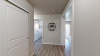 Located in the Harbour Landing community of Regina, Saskatchewan, this 2-bedroom, 1-bathroom unit offers a thoughtfully designed single-floor layout. The open-concept kitchen and living area serves as the heart of the space, featuring dark-stained cabinetry, light countertops with a breakfast bar accommodating two bar stools, black appliances including a refrigerator and range, and a subway tile backsplash. The kitchen flows seamlessly into the living room, which is bathed in natural light from a large sliding glass door fitted with vertical blinds. Light-toned laminate flooring extends throughout the unit, complementing the neutral grey and white wall palette.

The welcoming hallway, accented by decorative wall shelving, connects the living areas to the two bedrooms. Both bedrooms are cozy and functional, each featuring a window for natural light and overhead ventilation. The primary bedroom offers a quiet retreat with room for a full-sized bed and nightstands. The full bathroom includes a clean white tub-shower combination. The overall ambiance is modern and bright, with a consistent, contemporary aesthetic carried throughout every room.