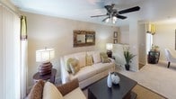 This single-story residence offers a thoughtfully designed layout that balances comfort and functionality across its key living spaces. The living room serves as the heart of the home, featuring a ceiling fan with integrated lighting, neutral walls, and plush carpeting. A sliding glass door with vertical blinds allows natural light to fill the room and provides access to an outdoor area, while decorative mirrors and framed artwork contribute to the warm, inviting ambiance.

Adjacent to the living room, the dining area accommodates intimate gatherings beneath a contemporary pendant light fixture, with a window that introduces additional natural light. The kitchen is efficiently arranged with dark granite-style countertops, dark wood cabinetry, a double stainless steel sink, and a black electric range. Wood-look flooring adds a grounded, practical touch to the space.

The bedroom is generously sized with carpeted floors, a ceiling fan, and a window offering outdoor views. A walk-in closet provides practical storage. The bathroom features wood-look flooring, a full tub-shower combination with white tile surround, and a vanity with granite-style countertops. A dedicated in-unit laundry area with a full-size washer and dryer and overhead shelving completes this well-rounded residence.