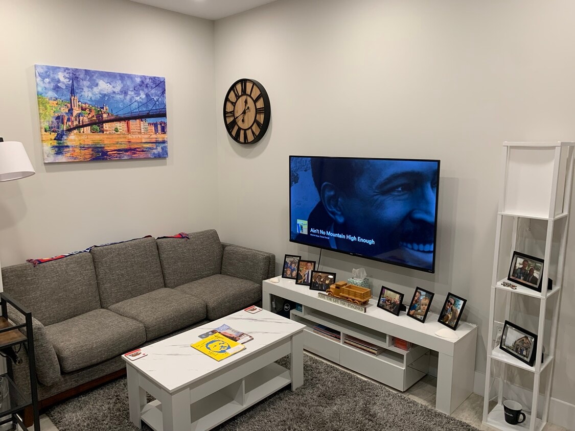 Furnished living room with coffee table and mounted 55" Smart TV. - 2556 University Pl NW