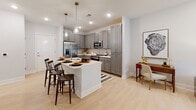 Located at 55 Gardner Dr on Hilton Head Island, SC, this well-appointed single-floor residence offers a thoughtfully designed open-concept layout filled with natural light and contemporary finishes. Light wood-style flooring flows throughout the main living areas, creating a seamless and cohesive feel.

The kitchen is a standout feature, showcasing grey shaker-style cabinetry, a white quartz countertop, subway tile backsplash, and a full suite of stainless steel appliances. A peninsula with seating for multiple guests serves as a natural gathering point and connects effortlessly to the dining and living areas. Pendant lighting adds a refined touch overhead.

The living room is bright and inviting, with large windows and a glass-paned door that allow ample natural light to fill the space. The room comfortably accommodates a variety of seating arrangements and opens to a versatile adjoining area that can serve as a sitting room or flex space.

The bedrooms are carpeted for comfort and benefit from generous natural light through well-placed windows. The primary bedroom includes access to a walk-in closet and an en suite bathroom featuring a dual-sink vanity with white countertops, grey cabinetry, and a tiled walk-in shower. The overall ambiance is clean, modern, and move-in ready.