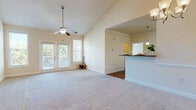 Located at 5001 Ballantyne Drive in Simpsonville, SC, this well-appointed 2-bedroom, 3-bathroom residence offers a thoughtfully designed single-floor layout. The combined kitchen and living room serves as the heart of the home, featuring warm hardwood-style flooring, crown molding, and a vaulted ceiling with a ceiling fan and access to a private balcony through French doors. The kitchen is equipped with rich honey-toned cabinetry, granite countertops, a full suite of black appliances including a refrigerator, range, microwave, and dishwasher, and a breakfast bar with pendant lighting. The living and dining areas offer plush carpeting and an elegant chandelier. The generously sized primary bedroom benefits from vaulted ceilings, a ceiling fan, French door balcony access, and ample natural light. The second bedroom features a large window with outdoor views and a pendant light fixture. Three bathrooms provide convenience, with finishes including granite-topped vanities and tub/shower combinations. A dedicated laundry room with washer and dryer hookups, a hallway, and a closet round out the functional layout of this comfortable Simpsonville residence.