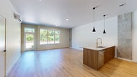 Located in Tigard, Oregon, this thoughtfully designed two-story residence offers 2 bedrooms and 2 bathrooms across two well-proportioned floors. The main level sets a contemporary tone with light oak hardwood flooring, a sleek open kitchen, and a combined living area. The kitchen is a standout feature, showcasing warm walnut cabinetry with brass hardware, white quartz countertops, stainless steel appliances, a deep single-basin sink with a gold-toned faucet, a mosaic tile backsplash, and stylish pendant lighting. An exposed concrete accent column adds an industrial touch that complements the modern aesthetic throughout. The upper level houses both bedrooms, carpeted for comfort, with the expansive primary bedroom offering a wall-mounted mini-split system, a generous closet, and large windows that fill the room with natural light and lush green tree views. The second bedroom also enjoys bright window views of the surrounding greenery. Both bathrooms are finished with walnut vanities, dual sinks, brass fixtures, and clean-lined mirrors. A dedicated laundry room with a stacked full-size washer and dryer adds everyday convenience, completing this polished and functional home.