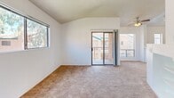 Located at 201 S Camino Seco in Tucson, Arizona, this one-bedroom, one-bathroom residence offers a well-designed layout with a variety of functional and comfortable spaces. The living room is a standout, featuring soaring vaulted ceilings that enhance the sense of openness, a tile-surround fireplace flanked by built-in shelving, and sliding glass doors that lead to a private balcony with views of the surrounding community. Multiple windows fill the room with abundant natural light, complemented by warm carpeted flooring. The kitchen and living area are seamlessly connected, with the kitchen offering a peninsula breakfast bar, wood-accented cabinetry with white upper panels, black appliances including a refrigerator, range, and built-in microwave, tile flooring, and a double-basin sink. Tall, narrow windows allow natural light to filter into the kitchen. The bedroom is a comfortable retreat with plush carpeting, a large sliding-door closet, and a window offering views of palm trees and the outdoor surroundings. The bathroom is straightforward and clean, featuring a tub-shower combination, a single-sink vanity with a mirror, and warm-toned tile flooring. A hallway connects the main living spaces, completing this efficiently designed single-floor unit.