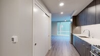 This 440 square foot apartment, located at 1940 Webster Street in Oakland, CA, offers a thoughtfully designed living space on a single floor. The unit showcases a modern aesthetic with an efficient layout that maximizes the available area. The open-concept design combines the kitchen and living room, creating a sense of spaciousness within the compact footprint.

The kitchen is equipped with sleek, dark wood cabinetry, stainless steel appliances, and a clean white backsplash. It features a full-size refrigerator, built-in microwave, and a range with oven, all seamlessly integrated into the design. The white quartz countertops provide ample workspace and contrast beautifully with the dark cabinetry.

The bathroom is well-appointed with a full-size bathtub and shower combination, modern fixtures, and coordinating wood vanity. The use of light-colored tiles and a glass shower door enhances the sense of space.

Throughout the apartment, wood-look vinyl flooring adds warmth and durability. Large windows in the living area flood the space with natural light and offer views of the surroundings. The neutral color palette of whites and grays creates a contemporary ambiance that can easily accommodate various decor styles.

Despite its compact size, the apartment's thoughtful design ensures functionality and comfort, making it an ideal urban dwelling in the heart of Oakland.