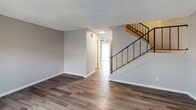 Located at 5810 Amaya in La Mesa, this two-story unit offers a well-organized layout across both levels. The main floor features durable wood-style flooring that flows throughout the open living area, which is anchored by a staircase with a sleek black metal railing. Natural light filters through a sliding glass door adjacent to the kitchen, creating a bright and inviting atmosphere.

The kitchen is a functional highlight, equipped with white shaker-style cabinetry, granite-patterned countertops, a double-basin sink, and a full suite of stainless steel appliances including a range, over-the-range microwave, dishwasher, and refrigerator. A tray ceiling with recessed lighting adds architectural interest to the space. A convenient half bathroom on the main level features a granite-topped vanity and wood-style flooring.

Upstairs, the bedrooms are finished with neutral carpet and textured ceilings, providing a comfortable setting. At least one bedroom includes a built-in sliding-door closet with shelving. A full bathroom on this level offers a tub-shower combination with chrome fixtures. Neutral gray tones throughout the unit create a cohesive and move-in-ready aesthetic.