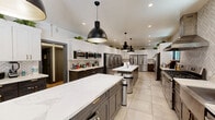 Located at 2425 Prospect St in Berkeley, CA, this thoughtfully designed shared kitchen delivers a professional-grade culinary environment in a single, efficiently organized floor. The space is anchored by a long central island with striking white marble-style quartz countertops, illuminated by bold black industrial pendant lights that add a modern edge to the overall aesthetic.

The kitchen is outfitted with an impressive array of stainless steel appliances, including multiple full-size French door refrigerators, a professional-grade range with a stainless steel hood, a built-in dishwasher, and several countertop microwaves — all designed to support high-volume, multi-user cooking. Dark espresso lower cabinetry with gold hardware is paired with crisp white upper cabinets, creating a sharp two-tone contrast. Lush green plants displayed atop the upper cabinets add a fresh, lively touch throughout.

A bold herringbone tile backsplash runs the length of the cooking wall, enhancing the contemporary design. Large-format light tile flooring keeps the space feeling open and clean. Natural light filters in through framed windows, brightening the workspace. The layout is practical and spacious, accommodating multiple users simultaneously with ease — making this kitchen a functional and visually impressive shared culinary hub.
