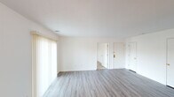 This single-floor residence offers a practical and well-organized layout designed for comfortable everyday living. The open living and dining areas are finished with light gray vinyl plank flooring, contributing to a bright and cohesive aesthetic throughout the common spaces. Large windows and a sliding glass door with vertical blinds allow natural light to fill the main living area, creating an airy and welcoming atmosphere. Textured ceilings are consistent throughout the home, adding a subtle design element to each room.

The kitchen is equipped with white cabinetry, light granite-style countertops, a double-basin sink, and black appliances including a range and dishwasher, offering both functionality and a clean visual contrast. A hallway connects the main living area to the private quarters of the home.

The bedrooms feature soft, neutral-toned carpeting and windows with blinds that provide natural light while maintaining privacy. Each room offers a comfortable and versatile space suitable for a variety of uses.

Two bathrooms serve the residence, each finished with vinyl plank flooring, white vanities, and clean white walls. One bathroom includes a shower-tub combination. Throughout the home, white panel doors with brass hardware provide a consistent finishing detail, tying the overall design together cohesively.