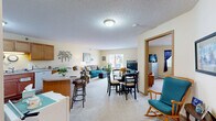 Located at 910 S Oak St in Cloquet, Minnesota, this single-floor residence offers a thoughtfully designed layout that maximizes comfort and functionality. The open-concept living and dining area forms the heart of the home, featuring soft carpeting, warm yellow-toned walls, and a textured ceiling. A sliding glass door in the living room fills the space with natural light and provides access to an outdoor area, creating a bright and welcoming atmosphere. The kitchen is well-equipped with warm wood cabinetry, white appliances including a range, refrigerator, and dishwasher, and a peninsula with bar seating that connects seamlessly to the dining area — ideal for casual meals or entertaining. The bedroom is a comfortable retreat, offering plush carpeting, a large closet with sliding wood doors, and a window dressed with curtains that allow for natural light. The full bathroom features warm wood cabinetry with a single vanity, tile-style flooring, a tub with shower, and generous wall space. Throughout the residence, the consistently warm color palette and practical finishes create a cohesive and inviting living environment suited for everyday comfort.