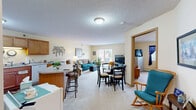 Located at 910 S Oak St in Cloquet, Minnesota, this single-floor residence offers a thoughtfully designed layout that maximizes comfort and functionality. The open-concept living and dining area forms the heart of the home, featuring soft carpeting, warm yellow-toned walls, and a textured ceiling. A sliding glass door in the living room fills the space with natural light and provides access to an outdoor area, creating a bright and welcoming atmosphere. The kitchen is well-equipped with warm wood cabinetry, white appliances including a range, refrigerator, and dishwasher, and a peninsula with bar seating that connects seamlessly to the dining area — ideal for casual meals or entertaining. The bedroom is a comfortable retreat, offering plush carpeting, a large closet with sliding wood doors, and a window dressed with curtains that allow for natural light. The full bathroom features warm wood cabinetry with a single vanity, tile-style flooring, a tub with shower, and generous wall space. Throughout the residence, the consistently warm color palette and practical finishes create a cohesive and inviting living environment suited for everyday comfort.