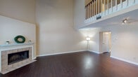 Located at 1127 Mallard Creek Rd in Louisville, KY, this two-story home offers a thoughtfully designed layout across two well-appointed floors. The main level greets you with a dramatic, double-height living area featuring rich, dark hardwood flooring, soaring walls, and a classic fireplace. Large windows allow natural light to fill the space, while a staircase with white-painted balusters and a wood railing leads to the upper level, which overlooks the living area via an open balcony. The kitchen is well-equipped with light wood cabinetry, granite-style countertops, stainless steel appliances including a range and microwave, a double sink, and a ceiling fan. A window at the end of the kitchen brightens the space with natural light. A half bathroom on the main level features a light wood vanity, neutral tile flooring, and classic lighting fixtures. Upstairs, the bedrooms are carpeted and receive ample natural light through multiple windows, with one bedroom offering access to a walk-in closet. The primary bathroom includes a dual-sink vanity with light wood cabinetry and a wide mirror with elegant vanity lighting. Throughout the home, neutral tones and consistent finishes create a warm, cohesive ambiance.