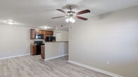 Located at 3706 W Idlewild Ave in Leto, FL, this one-bedroom, one-bathroom unit offers a practical and well-appointed layout across a single floor. The open-concept living, dining, and kitchen area forms the heart of the unit, finished with light wood-look luxury vinyl plank flooring and neutral-toned walls throughout. A ceiling fan with light fixture overhead serves both the living and dining areas, while a window allows natural light to fill the space. The kitchen features warm wood cabinetry, granite-style countertops, a peninsula with breakfast bar, and black appliances including a range, microwave, refrigerator, and dishwasher. A louvered closet door in the kitchen provides additional storage. The bedroom is carpeted for comfort, features a window with outdoor views, and is connected to a closet area. A second closet adds further storage convenience. In-unit laundry is also included. The bathroom is finished with tile-surround tub and shower combination, granite-top vanity with undermount sink, and matching wood-look flooring. A textured ceiling is consistent throughout the unit, adding a classic residential character to the overall design.