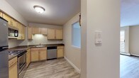 Located at 24 Bridle Path Cir in Randolph, Massachusetts, this single-floor residence offers a practical and comfortable layout designed for everyday living. The kitchen is well-appointed with light maple cabinetry, dark granite-style countertops, a stainless steel dishwasher, and an electric range. A pass-through window connects the kitchen to the main living area, enhancing the open feel between spaces. The living room features light wood-look flooring, a sliding glass door that invites natural light and provides views of surrounding wooded scenery, and a wall-mounted air conditioning unit alongside baseboard heating. A second carpeted living or sitting area offers additional flexibility, with dual windows framing natural views. The bedrooms are carpeted for comfort, with neutral warm-toned walls and generous closet space, including a walk-in closet in one bedroom. Two full bathrooms serve the unit, each featuring a tub-shower combination, wood-look tile flooring, and white cabinetry for storage. One bathroom includes a vanity with a white countertop and mirror. Throughout the residence, clean white trim, neutral wall tones, and consistent flooring choices create a cohesive and move-in-ready atmosphere suited for a variety of lifestyles.