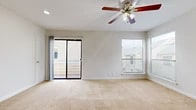 This single-floor residence offers a clean, functional layout designed for comfortable everyday living. The spacious living area is a standout feature, finished with plush wall-to-wall carpeting and bathed in natural light through dual windows and a sliding glass door that opens directly onto a private balcony, providing outdoor views of the surrounding neighborhood. A ceiling fan with integrated lighting adds both comfort and practicality to the space.

The entryway provides a welcoming transition into the home, featuring a combination of hardwood-style flooring and carpet, with a ceiling fan overhead and recessed lighting. The kitchen is efficiently laid out with dark cabinetry, light stone-look countertops, and hardwood-style flooring, alongside a full-size refrigerator and ample counter space for meal preparation.

The bedrooms are carpeted and well-proportioned, each equipped with ceiling fans and windows that allow natural light to filter in. The bathroom is finished with hardwood-style flooring and includes a full tub-shower combination with white tile surround, a toilet, and a vanity with a single sink and dark cabinetry with stone-look countertops. Throughout the residence, a neutral color palette of whites and warm beiges creates a cohesive and inviting atmosphere.