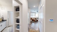 This single-story residence in Grapevine, Texas, offers a thoughtfully designed open-concept layout across three bedrooms and two bathrooms. A hallway entry introduces built-in shelving for convenient storage, leading into the main living areas finished with wood-style flooring throughout.

The kitchen serves as a focal point of the home, featuring white shaker cabinetry, granite countertops, a large center island with seating, stainless steel appliances including a French door refrigerator and wine cooler, a tile backsplash, and gold pendant lighting. The adjacent dining area benefits from corner windows dressed with sheer linen curtains, filling the space with natural light. The living room continues this brightness with large windows, a ceiling fan, and a warm, open feel.

The primary bedroom offers a ceiling fan, a sizable window, and comfortable proportions. Both bathrooms are finished with white vanity cabinetry, dark granite countertops, and framed mirrors. The two additional bedrooms provide flexible use of space. A dedicated closet offers supplemental storage. The overall aesthetic is contemporary and cohesive, with neutral tones and modern fixtures defining the character of the home.